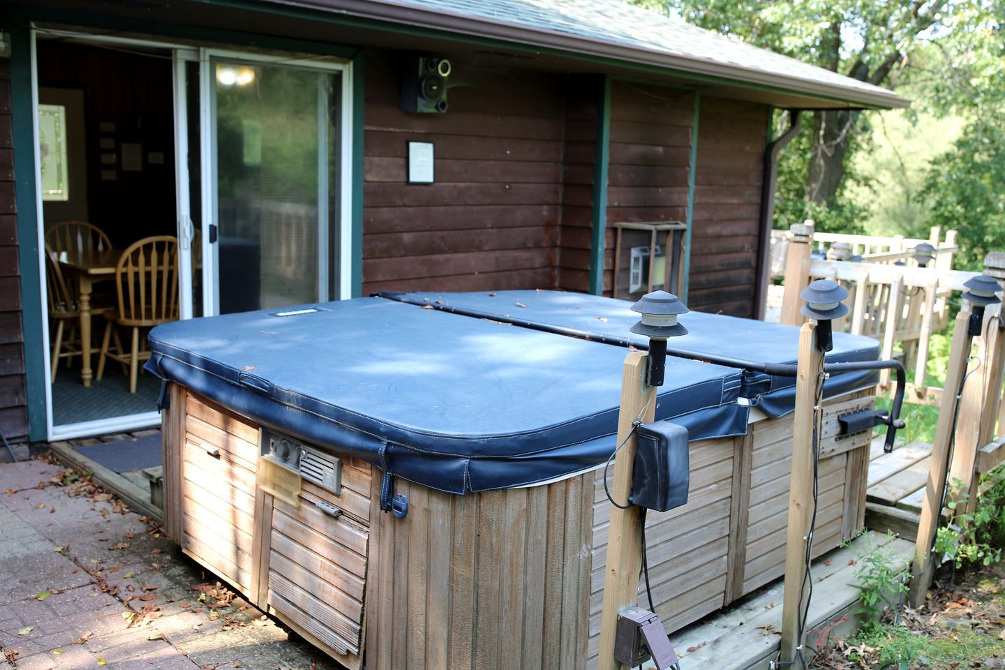 A hot tub with a wooden exterior, a sliding glass door, and a wooden deck.