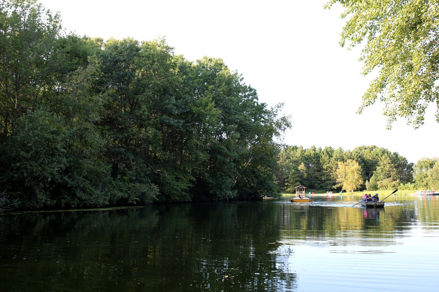 Ein ruhiger Fluss mit Booten, umgeben von dichtem Baumbestand.