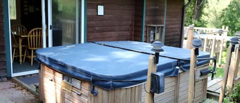 Un jacuzzi con revestimiento de madera, puerta corredera de vidrio y terraza de madera.