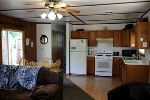 A compact kitchen with wooden cabinets, a stove, and a microwave. - Rustic Family Cabin Rental with a Fire Pit near Wisconsin Dells (Tomah)