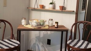Ein Eckzimmer mit zwei Holzstühlen, einem Tisch mit einem Korb, Regalen mit Topfpflanzen und an der Wand befestigten Schildern.