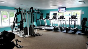 Ein Fitnessstudio mit unterschiedlichen Trainingsgeräten, darunter Laufbänder, Crosstrainer und Kraftgeräte.