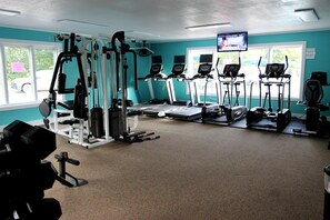 A gym with various exercise equipment, including treadmills, ellipticals, and weight machines. - Rustic Tree Top Cabin in Sky Valley, Georgia (Sky Valley)