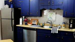 Eine Küche mit blauen Schränken, einem Edelstahl-Geschirrspüler, einer Spüle und einer Kaffeemaschine.