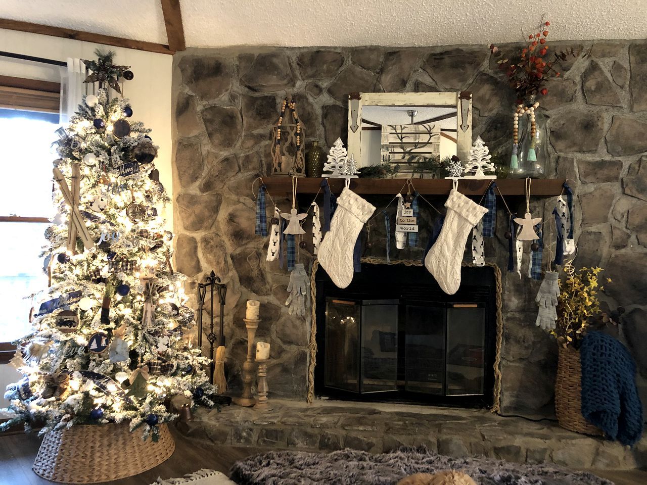 A cozy fireplace with stockings, a decorated Christmas tree, and rustic stone walls.