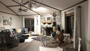 Ein gemütliches Wohnzimmer mit Kamin, eine Essecke mit Tisch und Stühlen sowie eine Sitzecke mit Sofa und Sesseln.