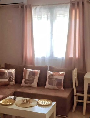A living room with a sofa, cushions, a small table with a decorative item, and a chair. - Cozy 2-bedroom apartment in tranquil Plazhi San Pietro with AC (Plazhi San Pietro)