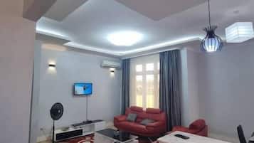 Una sala de estar moderna con una televisión de pantalla plana, un sofá rojo, una mesa de centro y un comedor con una mesa y sillas.