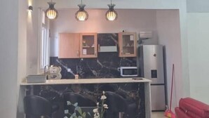 A dining area with a marble countertop, a central flower arrangement, and pendant lighting. - Legacy Homes 1B Apartment (Dar es Salaam)