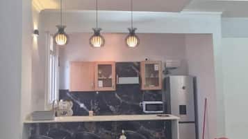 Comedor con encimera de mármol, un arreglo floral central e iluminación colgante.
