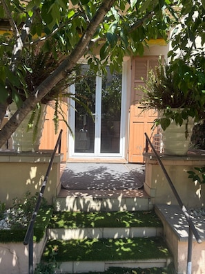 A set of outdoor steps leading to a door, surrounded by greenery and potted plants. - Garden apartment Cannes-Le Cannet (Le Cannet)