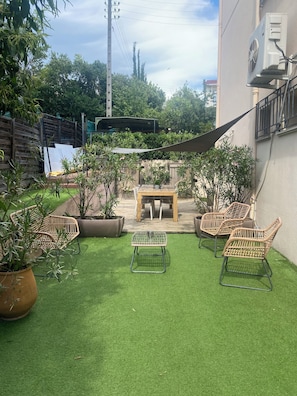 A patio with artificial grass, a wooden table, wicker chairs, and potted plants. - Garden apartment Cannes-Le Cannet (Le Cannet)