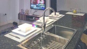 Una cocina moderna con iluminación colgante, un lavamanos empotrado y un televisor de pantalla plana.