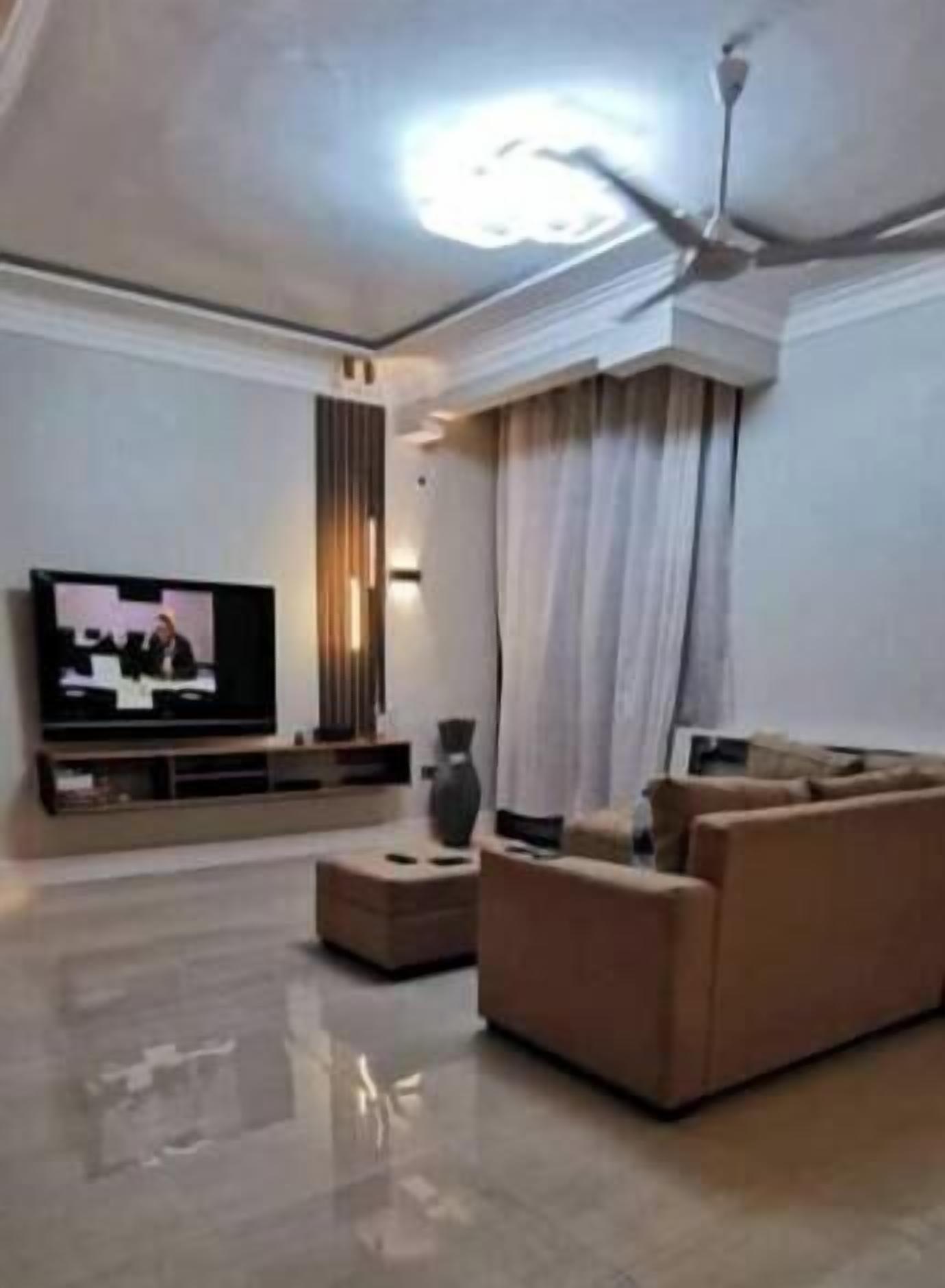 Un salon moderne doté d’un téléviseur à écran plat, d’un ventilateur de plafond, d’un canapé et d’une table basse.
