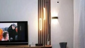 A modern living room with a flat-screen TV, a decorative light fixture, and a vase. - Legacy Homes 2A Apartment (Dar es Salaam)