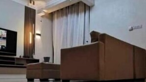 A hotel lobby with a reception desk, a ceiling fan, and a large window with curtains. - Legacy Homes 2A Apartment (Dar es Salaam)