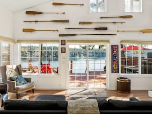 Una habitación con vista a un lago, remo de madera en la pared, un sofá y un sillón.