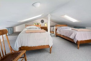 A bedroom with two wooden beds, a desk, and a chair.