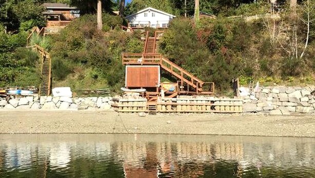 Una proprietà sul fiume con un molo di legno, una casa e un muro di sostegno in pietra.