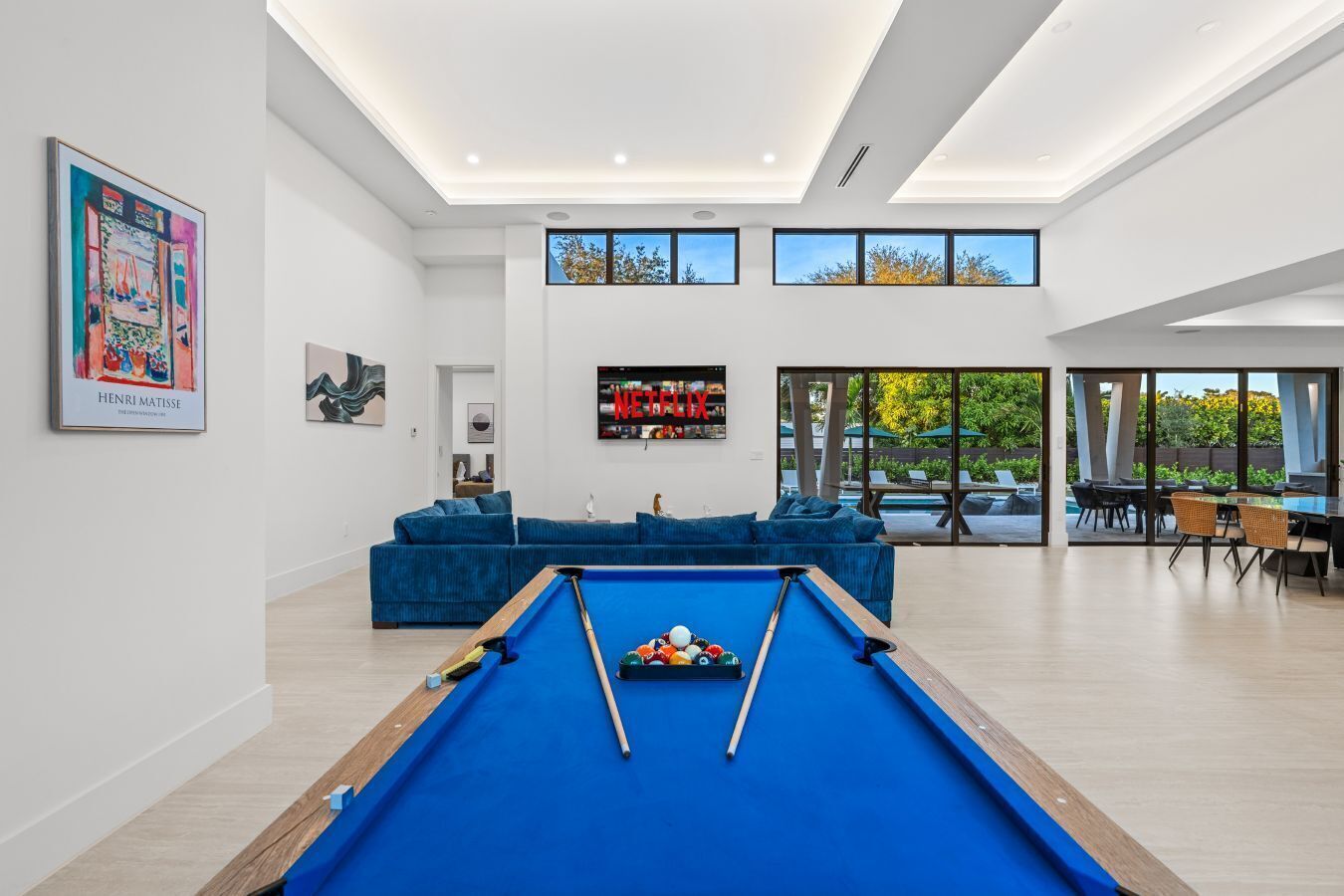 Un salon moderne avec une table de billard, un canapé bleu et un grand écran de télévision.
