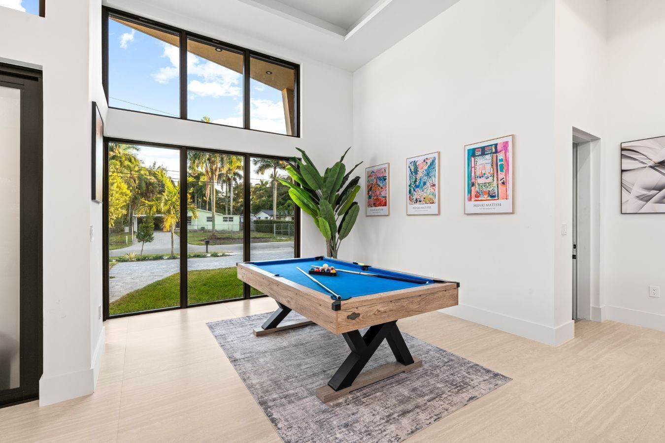 Ein moderner Innenraum mit Billardtisch, großen Fenstern und Kunstwerken an den Wänden.