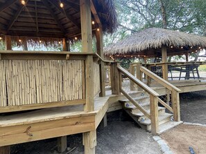 Une structure en bois avec un toit de chaume, un escalier et un mur en bambou.