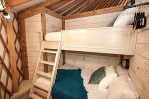 Un lit superposé avec une échelle, un petit bureau et une lampe suspendue.