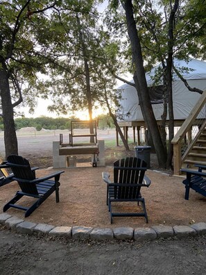Un espace extérieur aménagé avec des fauteuils Adirondack, une table en bois et un barbecue.