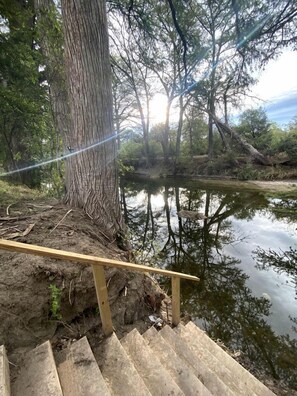 A wooden staircase leading down to a body of water, surrounded by trees and vegetation.