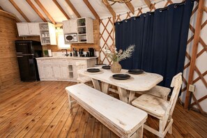Una cucina rustica con mobili in legno, un frigorifero nero e un tavolo da pranzo con sedie.