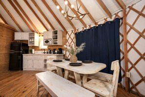 Una cocina rústica con armarios de madera, un refrigerador negro y una mesa de comedor con sillas.