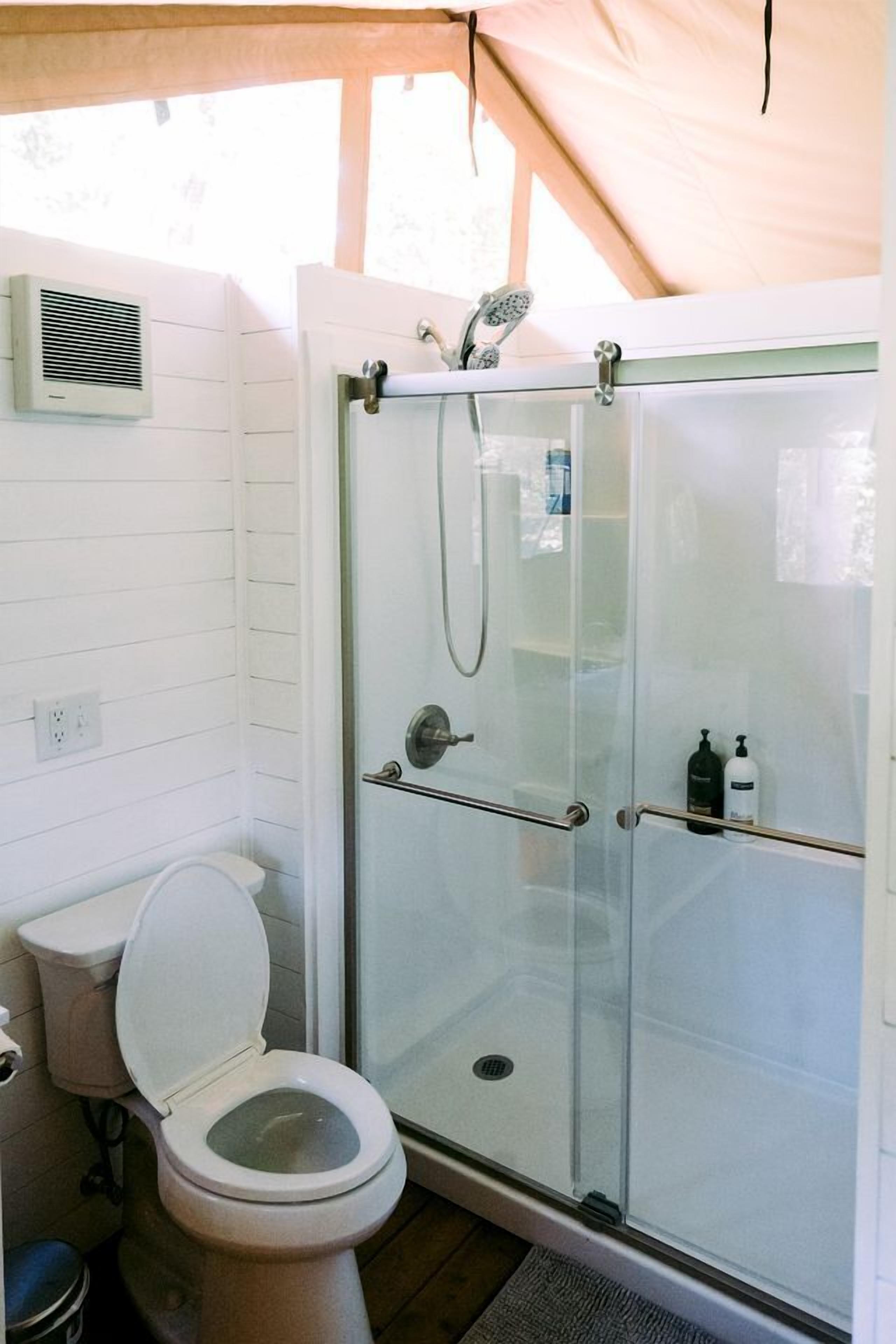 A bathroom with a glass-enclosed shower, a toilet, and a towel rack.