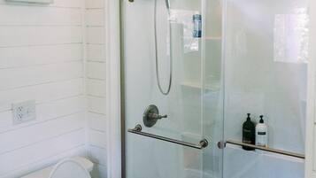 A bathroom with a glass-enclosed shower, a toilet, and a towel rack.