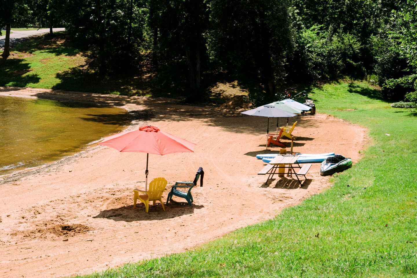 A beach with chairs, umbrellas, and a paddleboard.