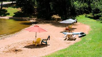 A beach with chairs, umbrellas, and a paddleboard.