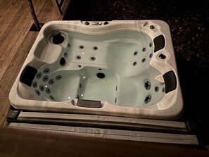 A hot tub with multiple jets, a built-in seat, and a drain cover.