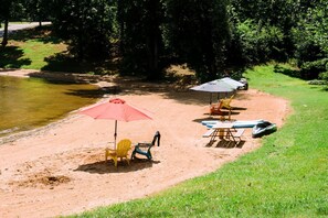 A beach with chairs, umbrellas, and a paddleboard.