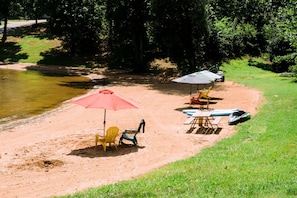 A beach with chairs, umbrellas, and a paddleboard.