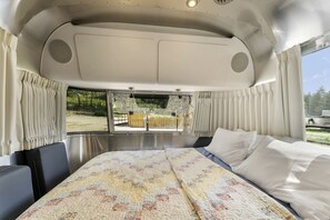 A spacious RV interior with a large bed, a dining area, and a view of the outdoors. - Fully-Equipped Airstream Rental for Glamping in Chelan, Washington (Chelan)
