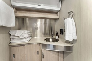 A compact bathroom with a sink, a towel rack, and a stack of towels. - Fully-Equipped Airstream Rental for Glamping in Chelan, Washington (Chelan)