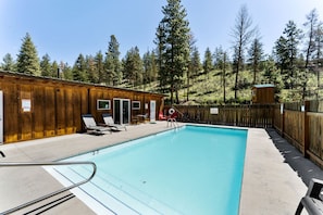 A pool area with wooden cabins, lounge chairs, and a clear view of the surrounding forest. - Fully-Equipped Airstream Rental for Glamping in Chelan, Washington (Chelan)