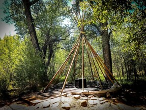 Un bosque con una estructura central hecha de postes de madera, rodeado de árboles.