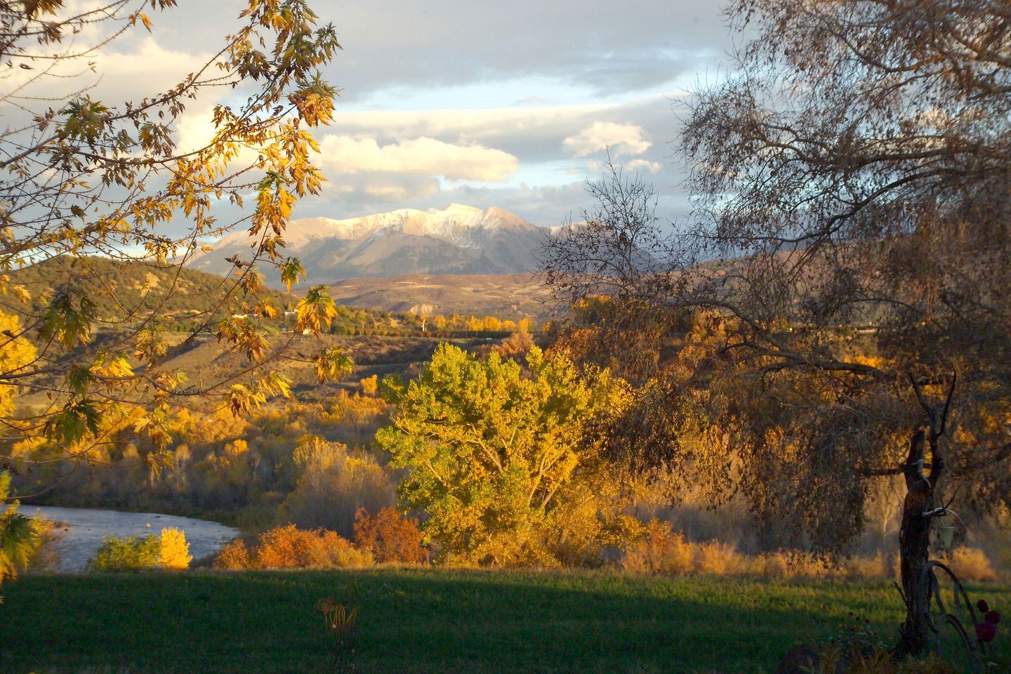 A mountainous landscape with autumn foliage, a river, and a bicycle in the foreground.