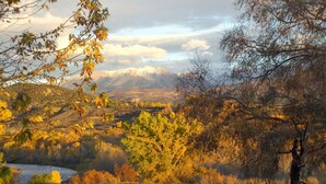 A mountainous landscape with autumn foliage, a river, and a bicycle in the foreground.
