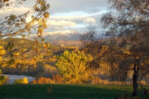 A mountainous landscape with autumn foliage, a river, and a bicycle in the foreground.