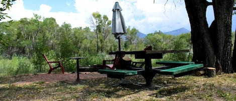 Un área de picnic con mesa, sillas y una sombrilla.