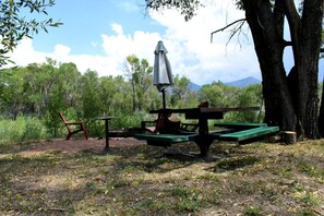 Un espace pique-nique équipé d’une table, de chaises et d’un parasol.