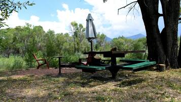 A picnic area with a table, chairs, and an umbrella.