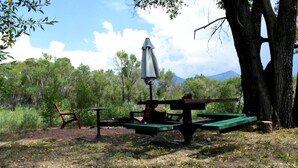 A picnic area with a table, chairs, and an umbrella. - Riverside Campsite in Colorado (Paonia)
