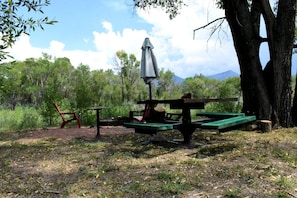 Un área de picnic con mesa, sillas y una sombrilla.